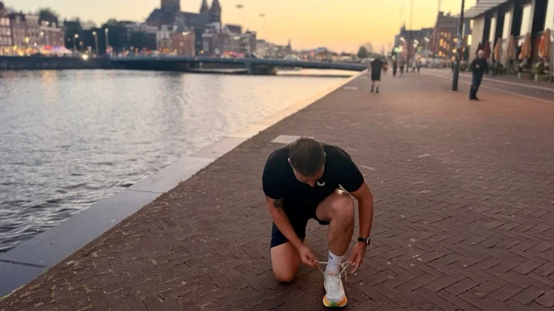 Tying running shoes by the Amsterdam waterfront at sunrise